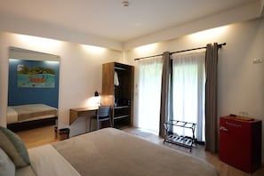 A bedroom with a bed, a desk, a chair, a wardrobe, a radiator, and a window with curtains. - PALAKA RESORT (General Luna)
