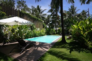 A swimming pool with lounge chairs and an umbrella, surrounded by lush tropical vegetation. - PALAKA RESORT (General Luna)