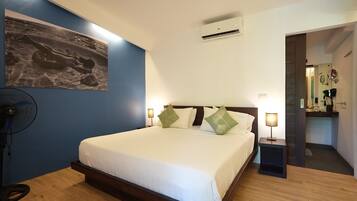 Habitación de hotel con cama, lámparas de noche, aire acondicionado de pared y ventilador.