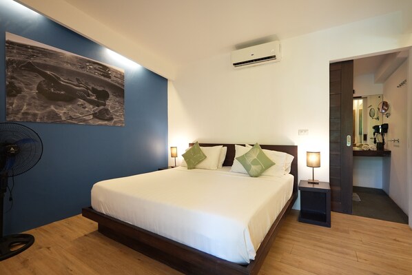 A hotel room with a bed, bedside lamps, a wall-mounted air conditioner, and a fan. - PALAKA RESORT (General Luna)