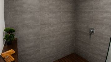 A modern shower with grey tiles, a wooden floor, and a small plant on a shelf.