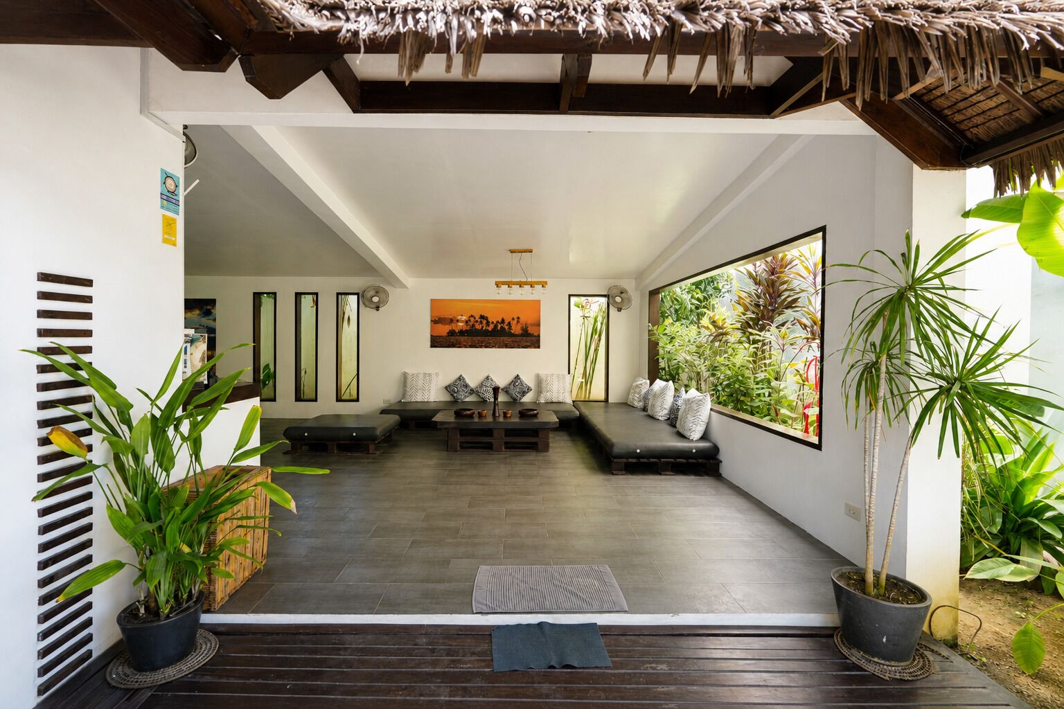 Un interior moderno con una zona de estar, ventanas amplias y plantas en macetas.