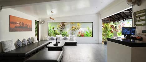 A modern living room with a sofa, a coffee table, and a large window with a view of plants.