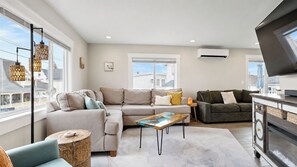 A modern living room with a sectional sofa, a coffee table, and a TV stand. - Salt & Soul Retreat by Bayley Vacation Rentals (Old Orchard Beach)