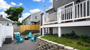 A backyard with outdoor seating, a fire pit, and a wooden deck. - Salt & Soul Retreat by Bayley Vacation Rentals (Old Orchard Beach)