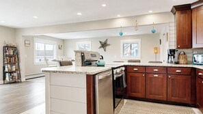 A modern kitchen with a central island, built-in appliances, and wooden cabinetry. - Salt & Soul Retreat by Bayley Vacation Rentals (Old Orchard Beach)