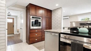 A modern kitchen with wooden cabinets, stainless steel appliances, and a granite countertop. - Salt & Soul Retreat by Bayley Vacation Rentals (Old Orchard Beach)