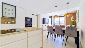 Uma cozinha moderna com uma ilha central, forno embutido e área de jantar com mesa e cadeiras.