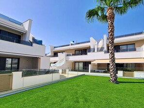 A modern residential building with multiple balconies, a well-maintained lawn, and a palm tree. - Private Roof Terrace & Pool View Penthouse (Mar de Cristal)