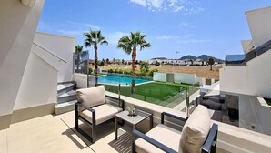Uma varanda com piscina, móveis de exterior e vista para uma área residencial.