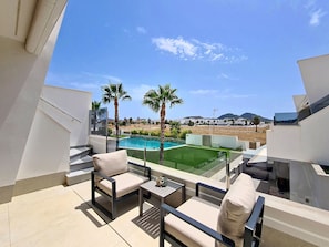 Ein Balkon mit Pool, Gartenmöbeln und Blick auf ein Wohngebiet.