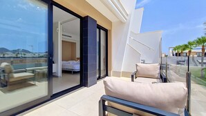 Quarto de hotel moderno com varanda, cama e vista para o horizonte da cidade.
