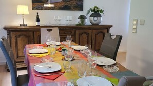 A dining area with a table set for four, a painting above, and a lamp on the side. - Holiday Home 'Am See' with Lake View, Private Terrace and Private Garden (Sundern)