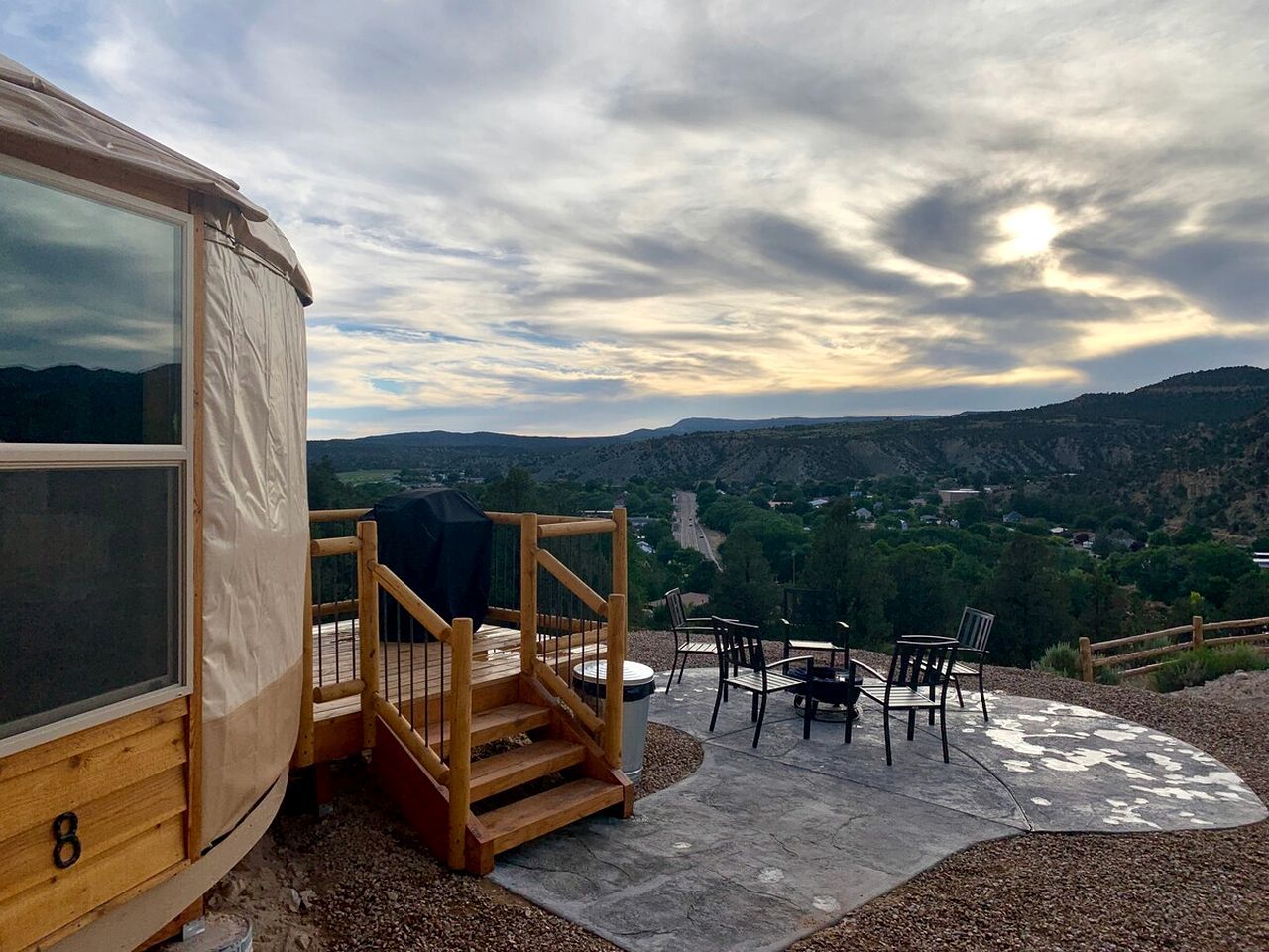 Eine Holzterrasse mit Sitzgelegenheiten und Blick auf eine gebirgige Landschaft.
