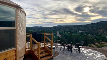 Eine Holzterrasse mit Sitzgelegenheiten und Blick auf eine gebirgige Landschaft.