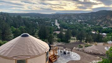 A yurt with a concrete patio, outdoor seating, and a view of a valley.