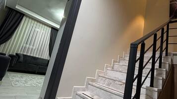 Eine Treppe mit Marmorstufen und schwarzen Geländern, die zu einer Zwischenebene im zweiten Stock führt.