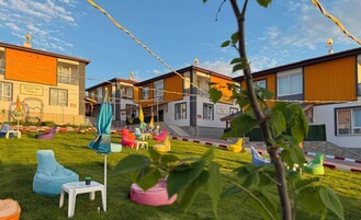Un barrio residencial con casas modernas, un césped y muebles de jardín coloridos.