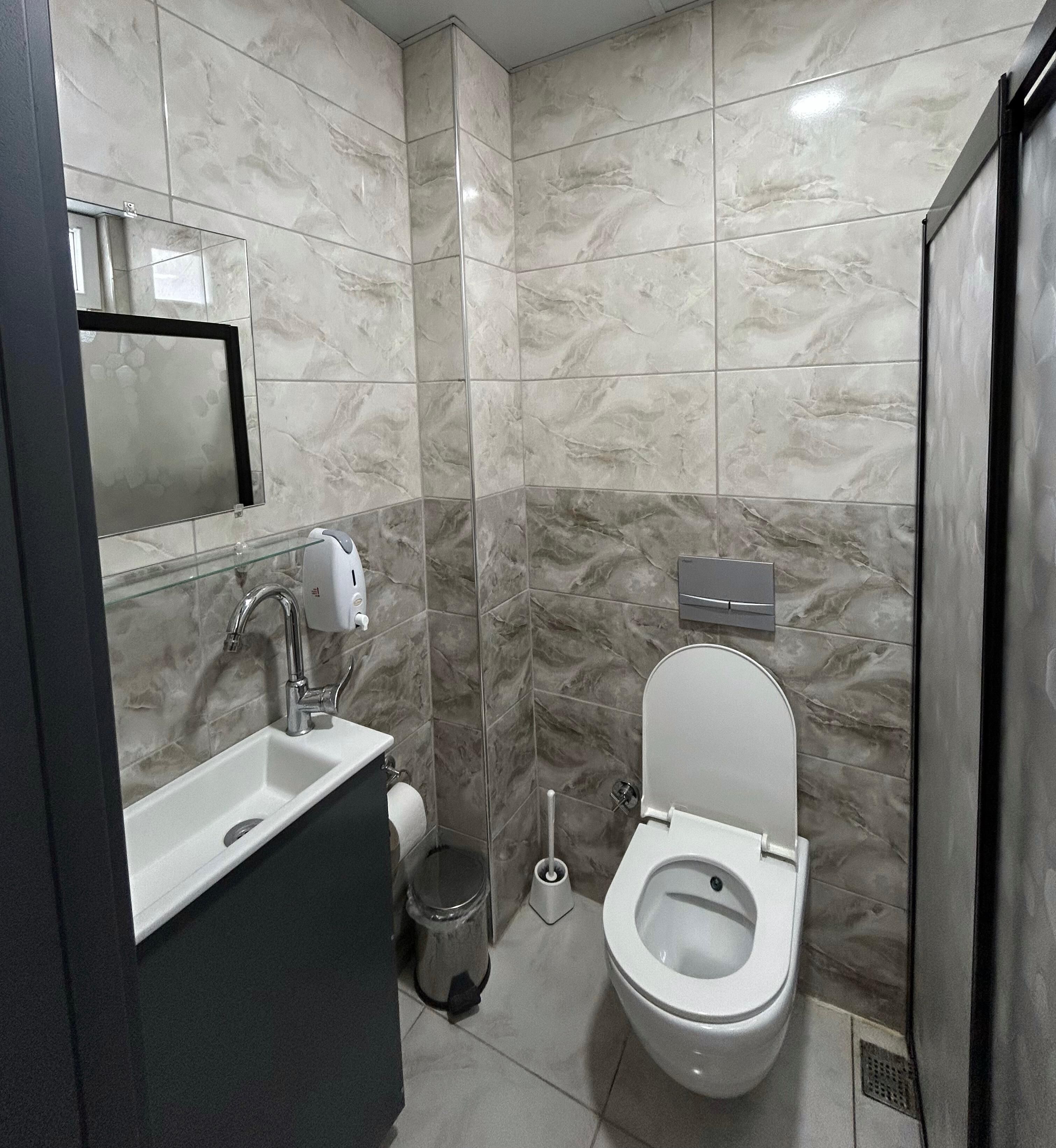 A modern bathroom with a toilet, sink, and hand dryer.