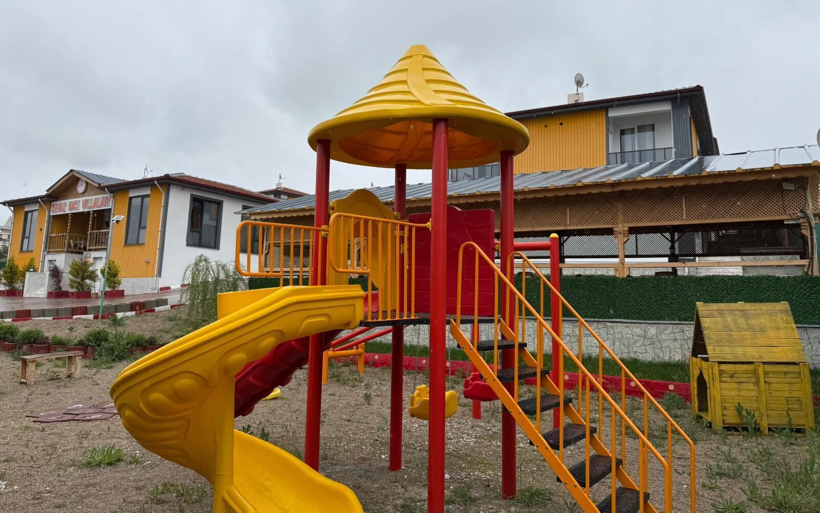 Un parque infantil con un tobogán amarillo y estructuras de escalada rojas.