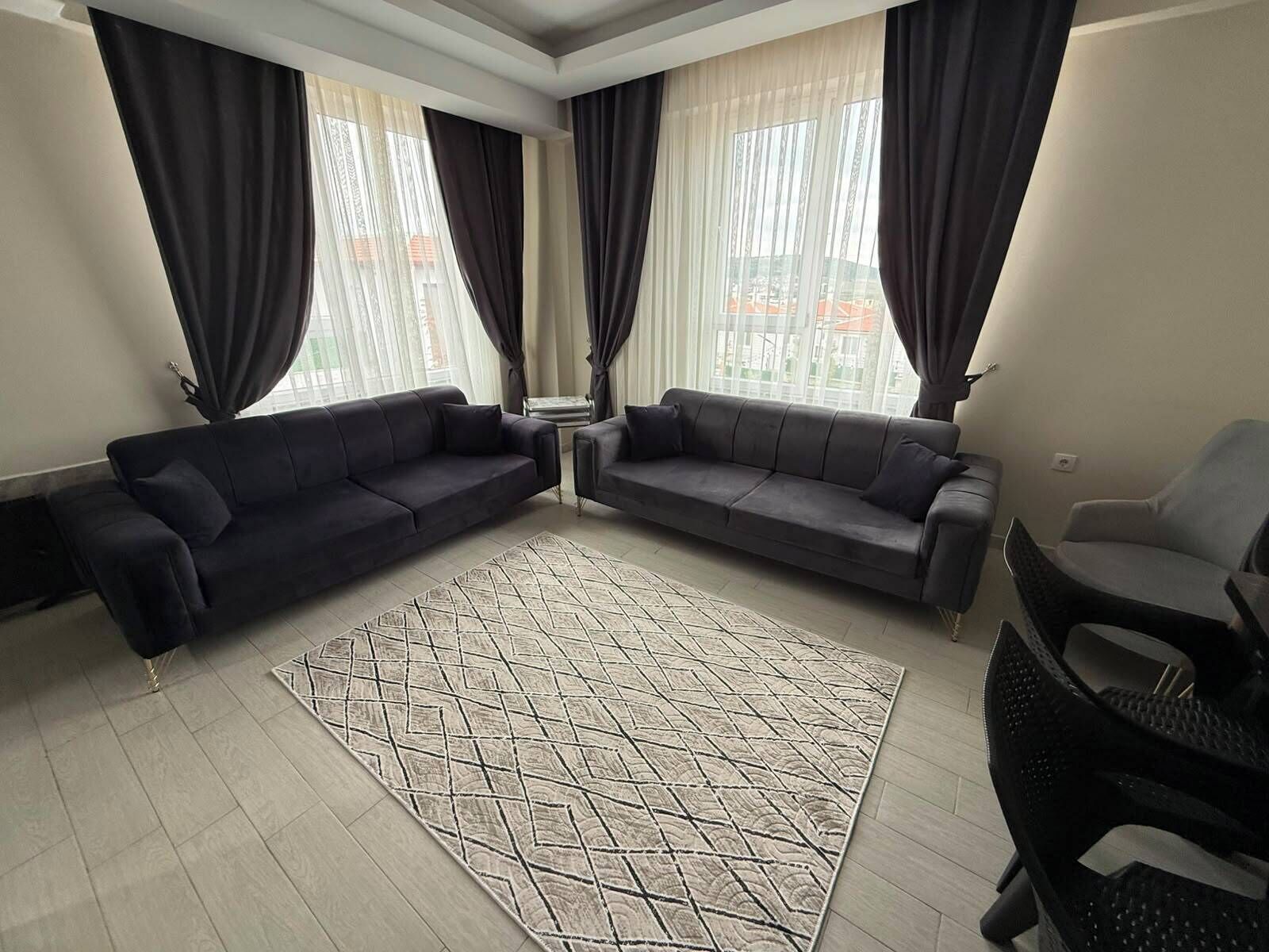 Una sala moderna con dos sofás, un tapete estampado y un sillón.
