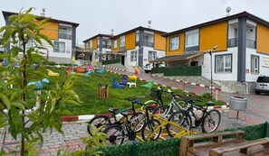 Zona residencial con casas modernas, un patio cubierto de césped y bicicletas estacionadas.