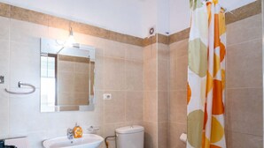 A bathroom with a sink, toilet, bathtub, and shower curtain. - Albania Dream Saranda Apartment (Sarandë)