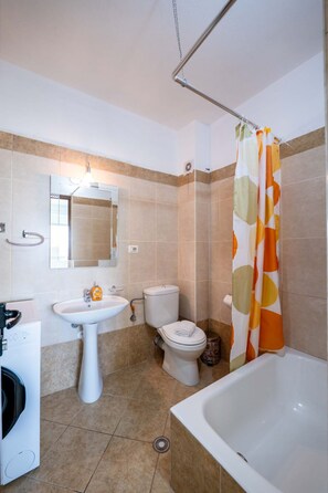 A bathroom with a sink, toilet, bathtub, and shower curtain. - Albania Dream Saranda Apartment (Sarandë)