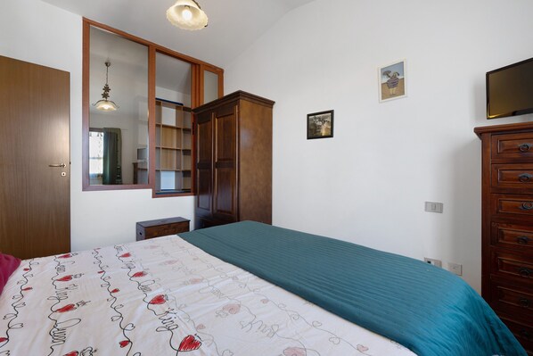 A bedroom with a bed, a wardrobe, a dresser, and a mirror.