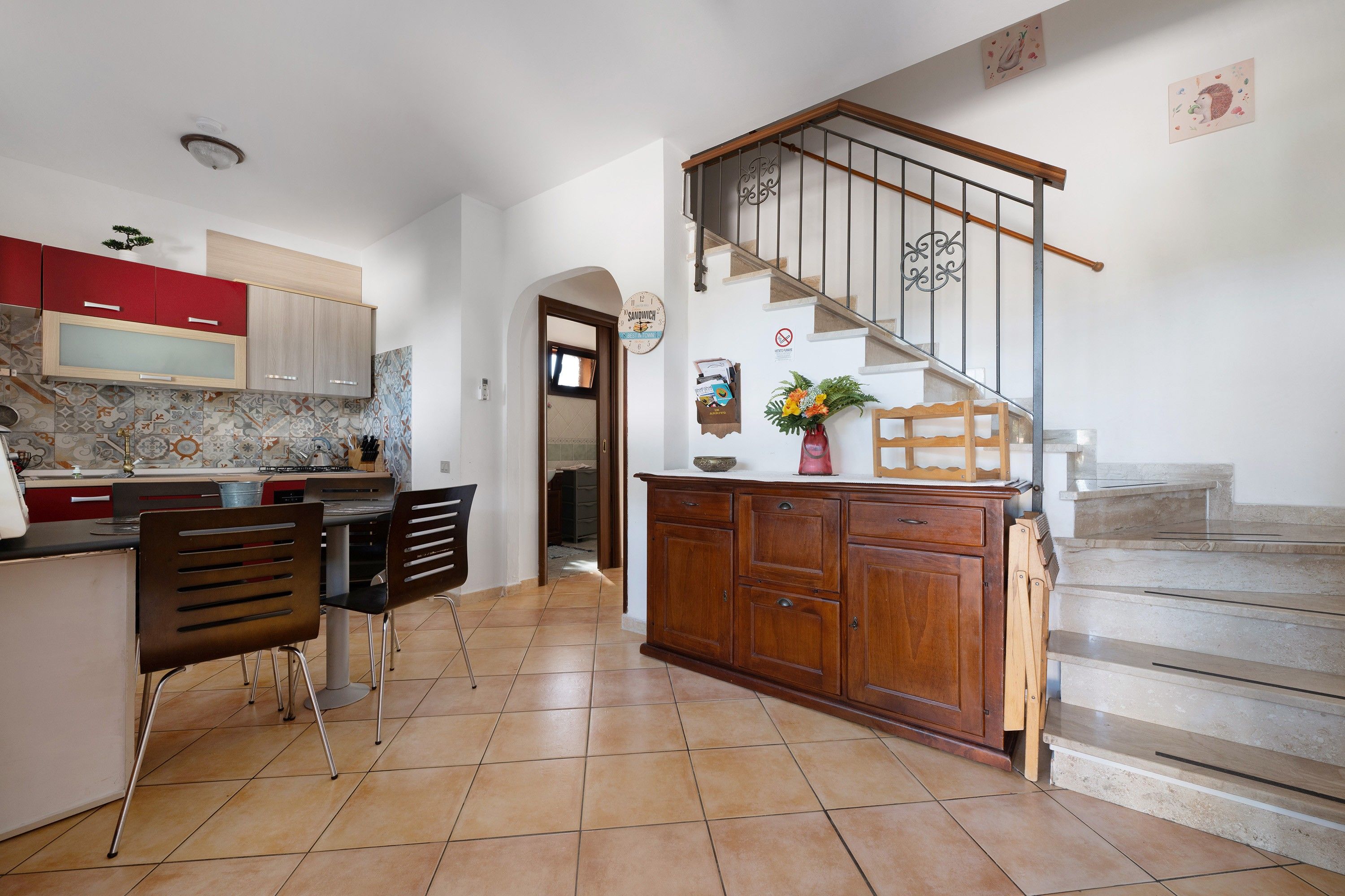 Une cuisine avec un coin repas, un escalier et un couloir menant à une autre pièce.