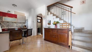 Une cuisine avec un coin repas, un escalier et un couloir menant à une autre pièce.