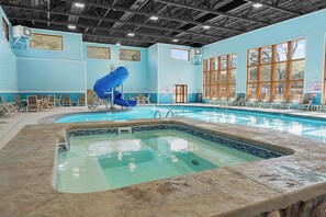 Ein Hallenbad mit blauer Rutsche, Sitzgelegenheiten und großen Fenstern.