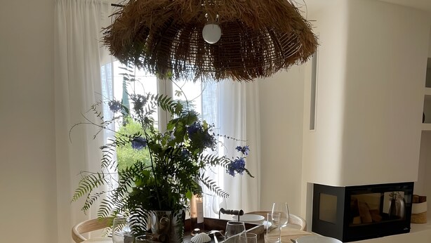 A dining area with a round wooden table, white plates, and a hanging basket with dried plants. - 4-Bedroom Villa with Private Pool near the Sea, Wi-Fi, and Air Conditioning (Saint-Raphaël)