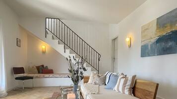 A modern living room with a staircase, a sofa set, a coffee table, and a painting on the wall.