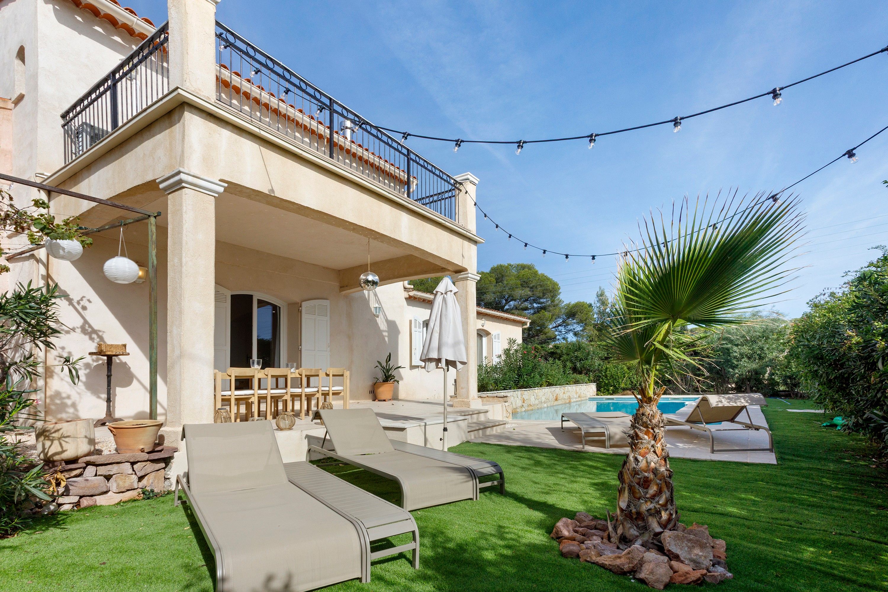 A villa with a pool, outdoor seating, and string lights.