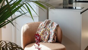Una cocina moderna con una mesa redonda de madera, una silla con cojín floral y una planta en maceta.