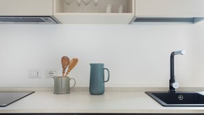 Una cocina moderna con un lavabo negro, una taza azul y una cuchara de madera en una taza verde.