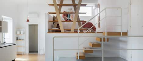 Un interior moderno con una escalera, una zona de cocina y un espacio para la sala.