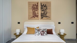 Una habitación de hotel con una cama, dos mesitas de noche y dos lámparas de pared.