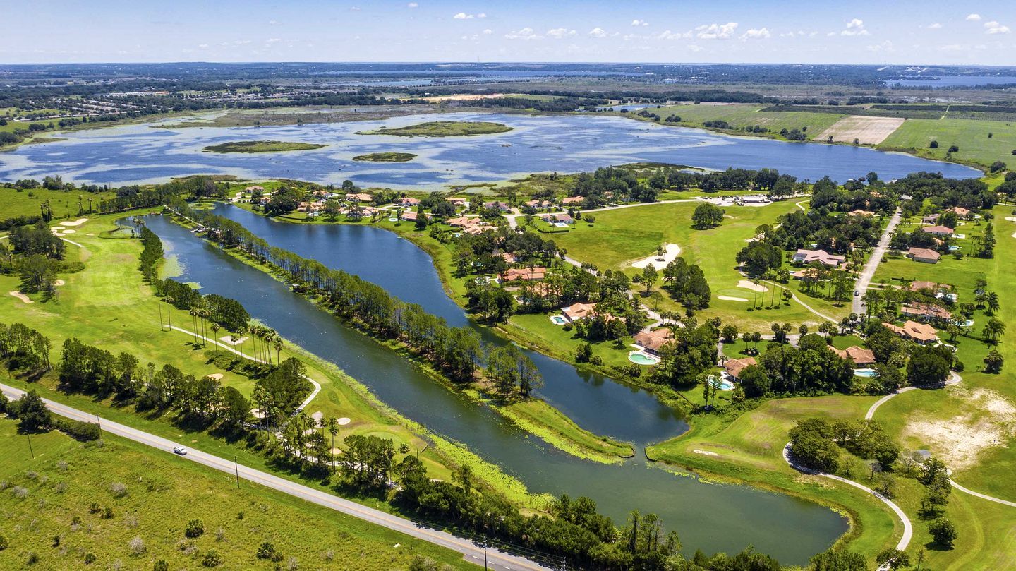 An aerial view of a golf course with multiple water bodies and residential areas.