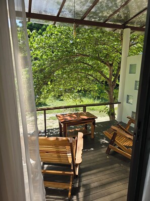 A wooden deck with a table and chairs, surrounded by lush greenery. - The Last Paradise (Ko Lanta)
