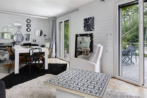 A modern interior with a dining area, a large mirror, and a view through a sliding glass door.