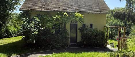 Una casa de un piso con techo inclinado, puerta principal y un pequeño porche.