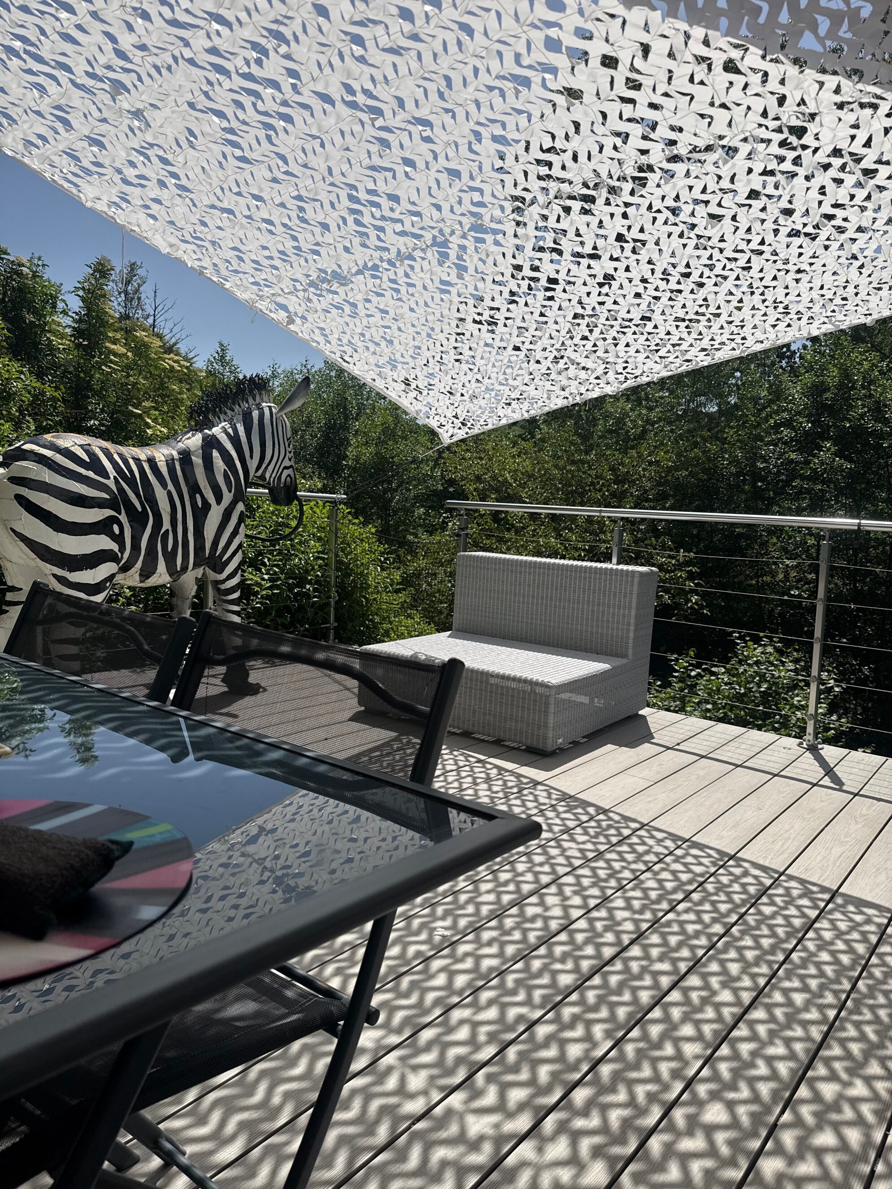 Een terras buiten met een zebrabeeld, rieten meubels en een versierd plafond.