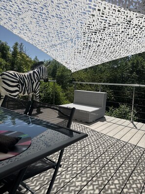 An outdoor patio with a zebra sculpture, wicker furniture, and a patterned ceiling.