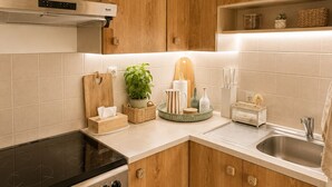A kitchen with wooden cabinets, a black stove, a sink, and various kitchen items. - Casa Arletta | 4 people | AC | private parking | free Wi-Fi | beaches within walking distance (Les saintes maries de la mer)