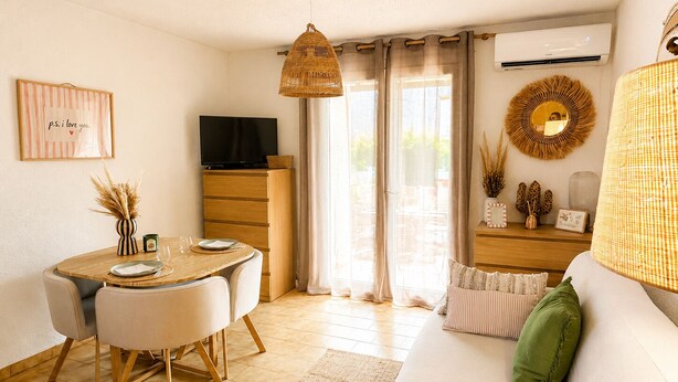A modern living room with a dining area, a television, and a sofa with decorative pillows. - Casa Arletta | 4 people | AC | private parking | free Wi-Fi | beaches within walking distance (Les saintes maries de la mer)