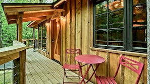 Een houten chalet met terras, een tafel en twee stoelen.