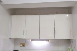 A kitchen with white cabinets, a light fixture, and a power outlet. - Cosy Studio in a Quiet, Accessible Setting (Nairobi)