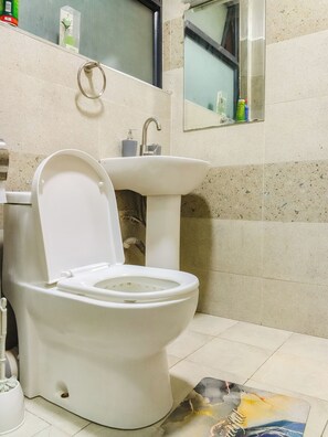 A bathroom with a toilet, sink, and a mirror. - Cosy Studio in a Quiet, Accessible Setting (Nairobi)